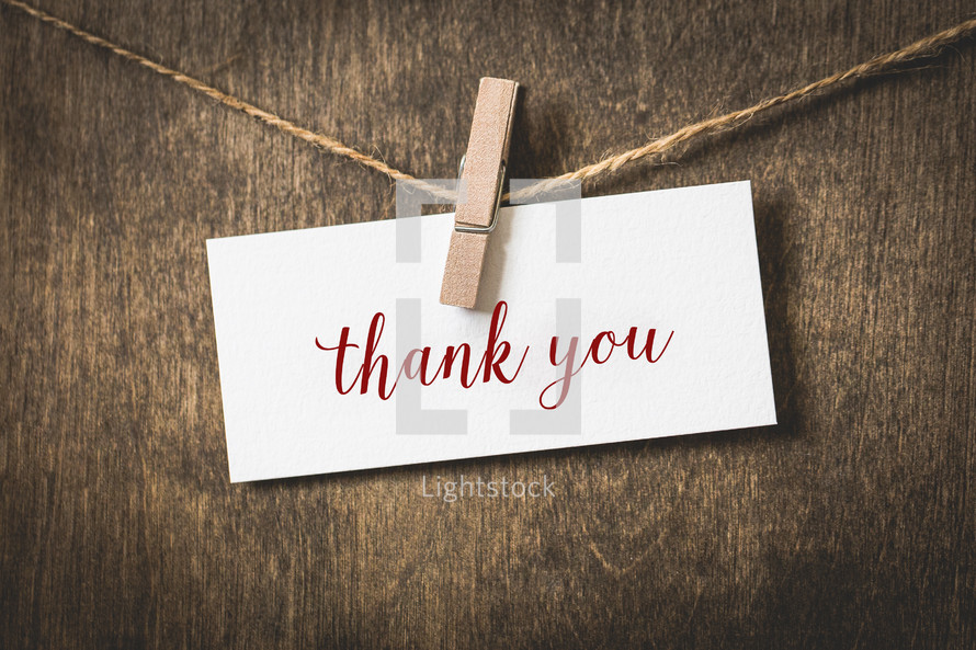word thank you on white card stock hanging from a clothespin on a clothesline 