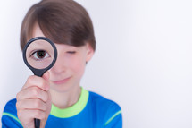 Boy with a magnifying glass to his eye.