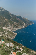 houses and churches on a mountainside along a coastline in Italy 