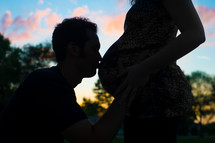 silhouette of a man kissing a pregnant woman 