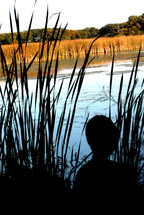 silhouette of a boy near a pond