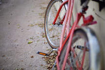 Shallow focus of a red bicycle leaning against a cinder block wall.