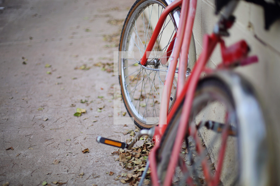 Shallow focus of a red bicycle leaning against a cinder block wall.