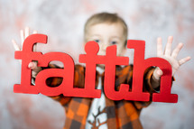 toddler boy holding the word faith