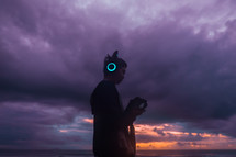 man listening to headphones on a beach with LED lights 