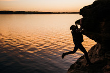 a man climbing a rock a sunset 