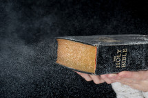 blowing off dust from a Bible 