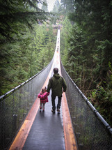 father and toddler daughter crossing a swinging bridge 