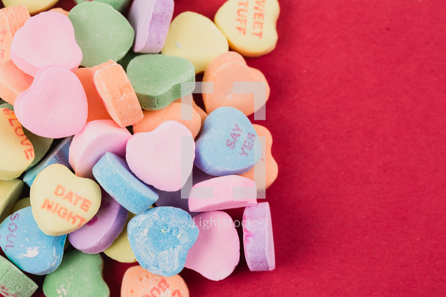 Multi-colored candy hearts with Valentine messages on a red background.