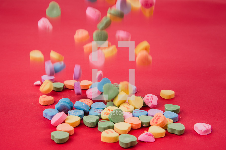 conversation hearts spilled on a red background 