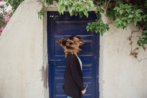 woman shaking her head standing in front of a blue door 