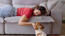 Portrait of a Woman laying on a Couch, Petting her Dog and Spending Time Bonding with Him. Lovely Cute Moment Shared Between Owner and Lovely mixed breed dog, Caressing and Kissing
