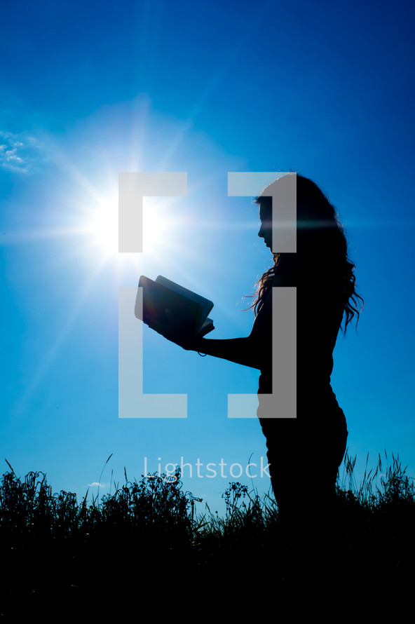silhouette of a woman reading a Bible 