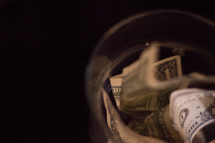 closeup of money stuffed in a jar