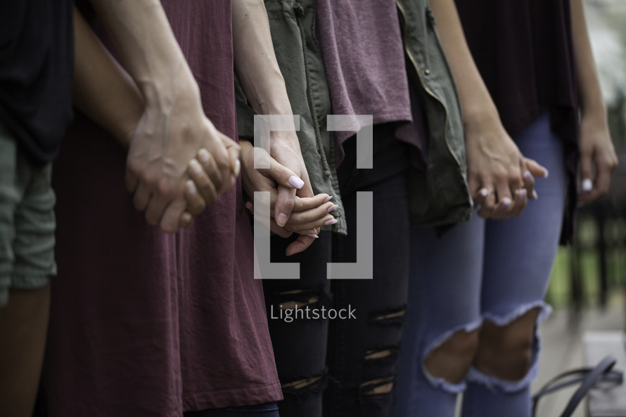 women holding hands in prayer at a Bible study 