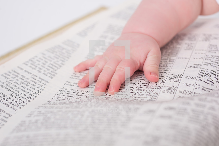 Baby's hand laying on an open bible