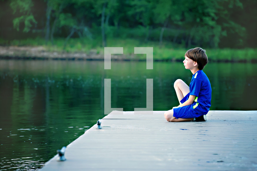 boy child on a dock by a lake 