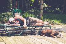 a man resting on a lounge chair next to a bulldog 
