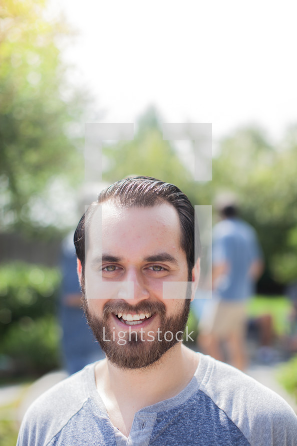 headshot of a man and friends talking at a backyard summer party