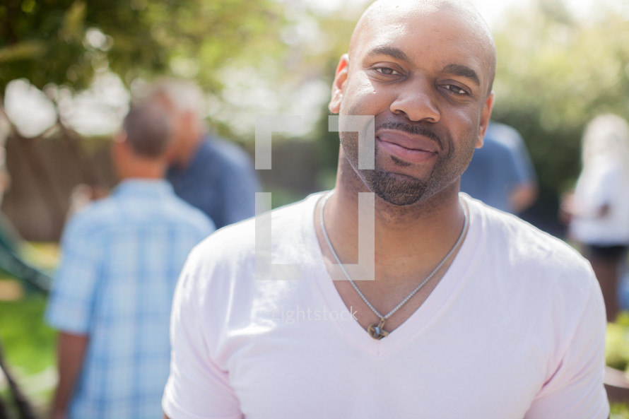 headshot of an African American man and friends talking at a backyard summer party