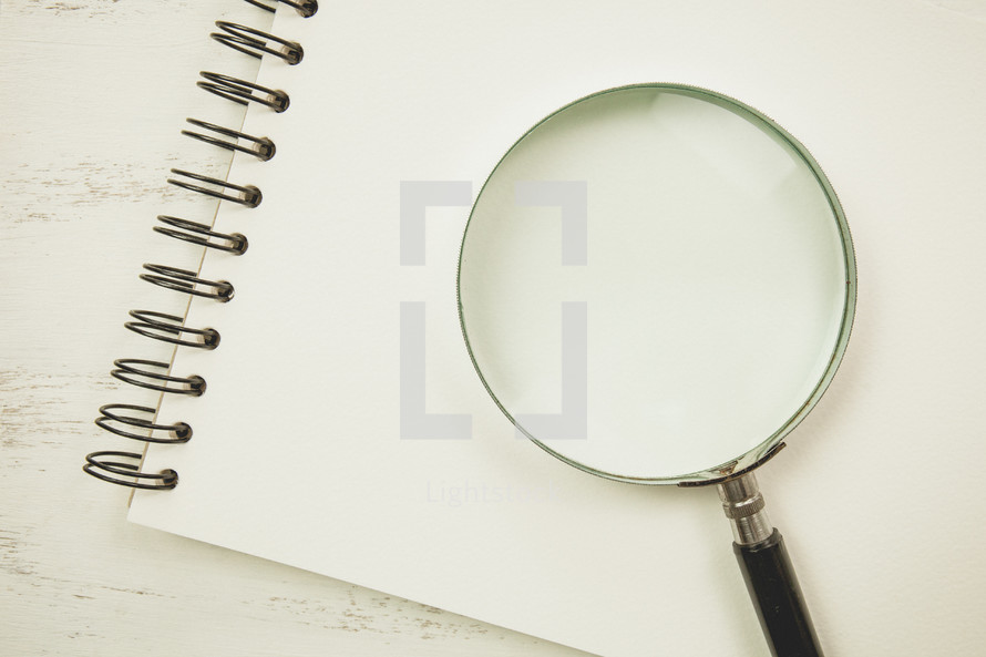 magnifying glass on a blank sketchpad 