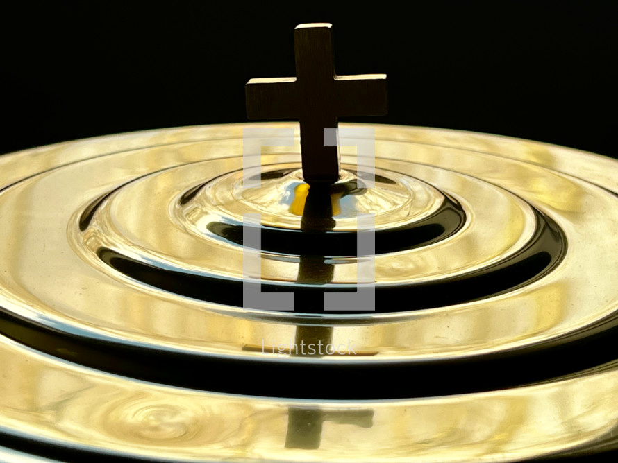 cross in gold on a communion tray 