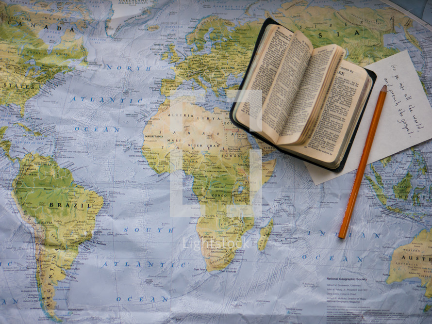 a Bible, notepad, and pencil on a map 