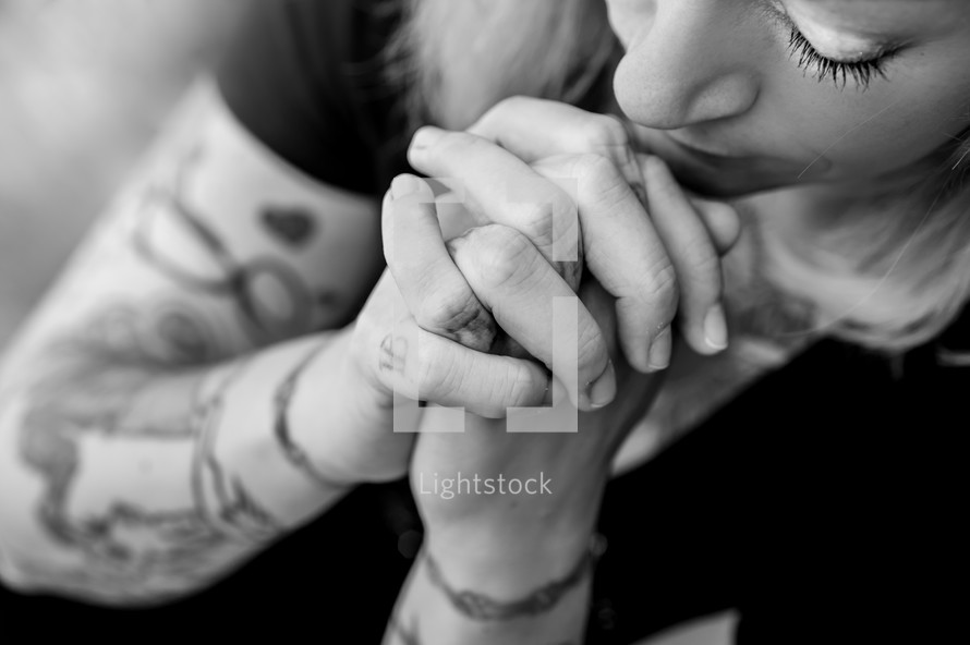woman with tattooed hands praying 