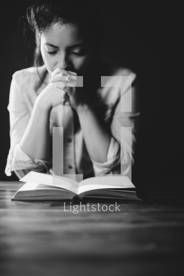 woman praying over a Bible 