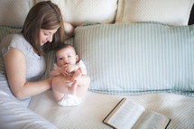 Mother and daughter on a bed with an open Bible.