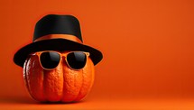 Halloween pumpkin wearing black hat and sunglasses on orange background. 3D Rendering