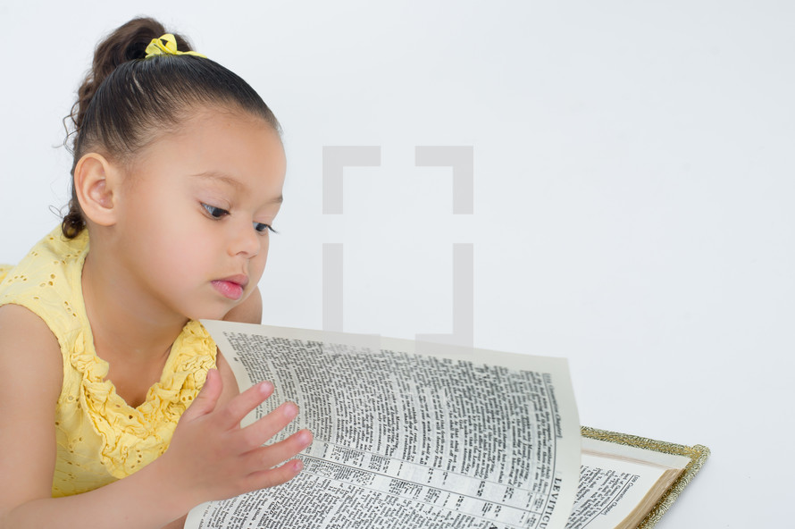 Little girl reading a Bible.