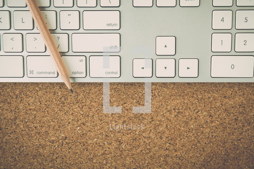 a pencil, keyboard, and cork board 