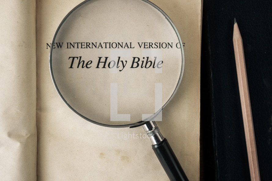 magnifying glass over Bible - The Holy Bible title page 