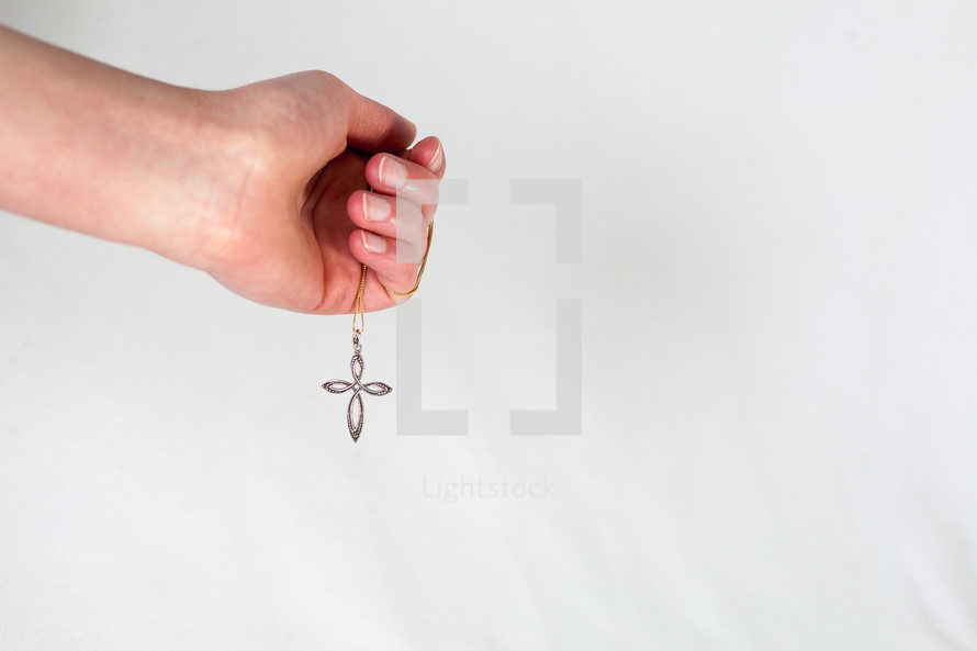 hand holding a cross necklace 