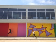 man and woman running and jumping in front of abstract painted walls