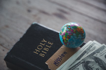 Globe and money with a Bible