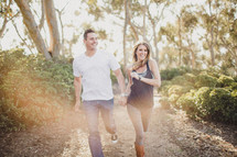 Couple running through the woods in a ray of sunshine.