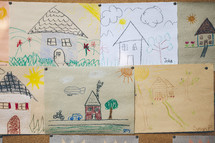 children's drawings of house on a cork board 