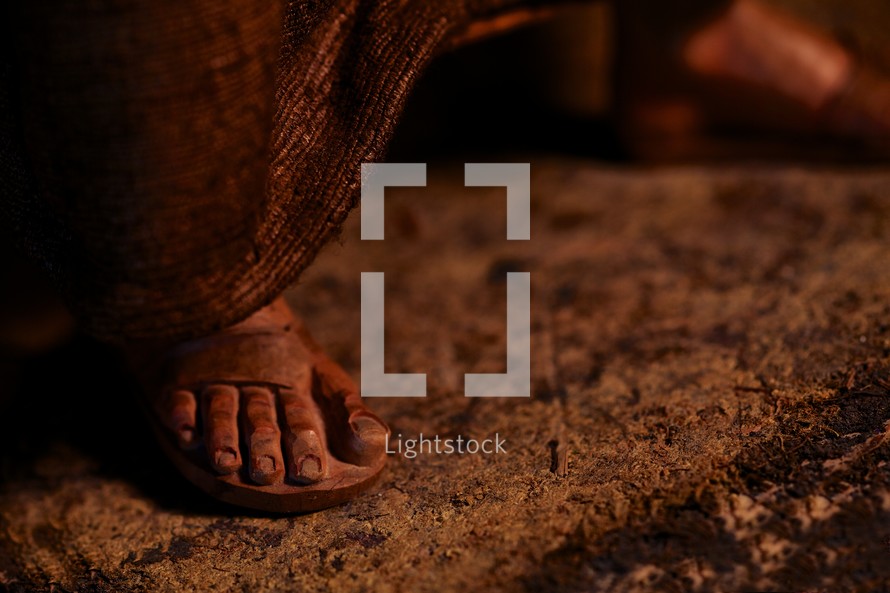 The feet and sandals of a shepherd boy from a nativity set.