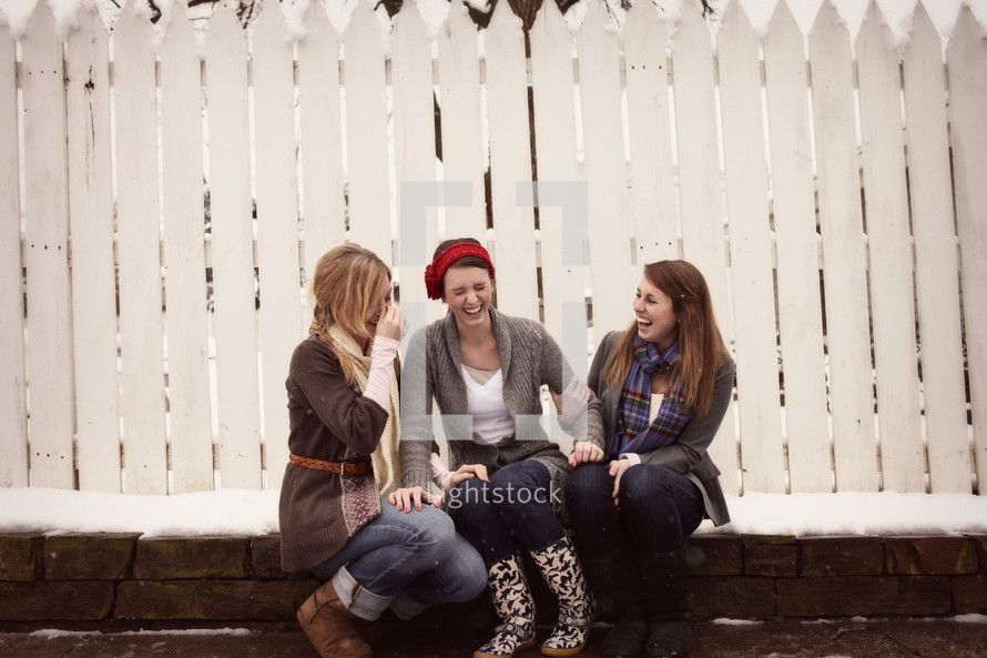 teen girls giggling in front of a white fence