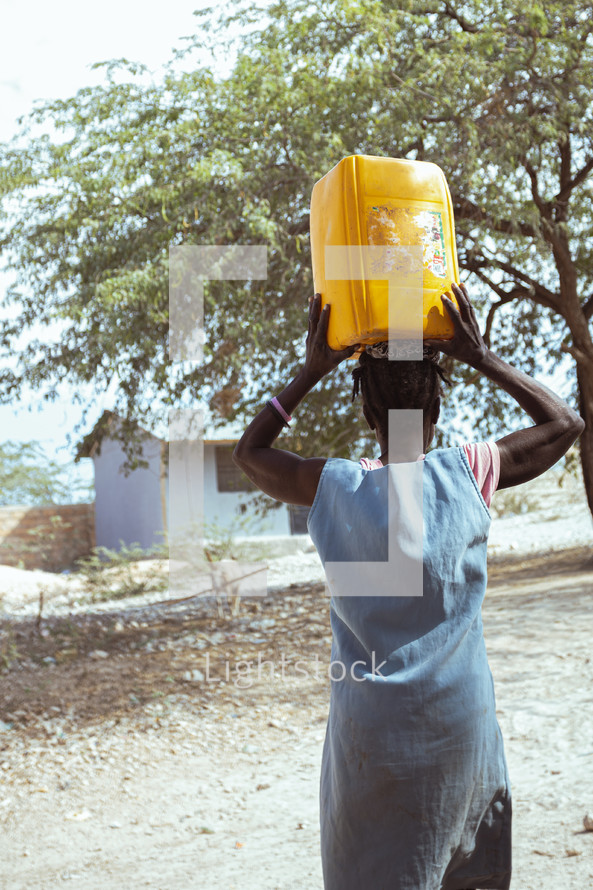 A woman in Haiti carrying a water jug on her head