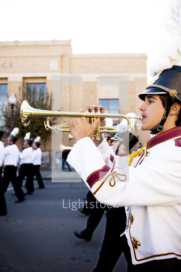 Boy playing trumpet with school band marching on street competition  brass