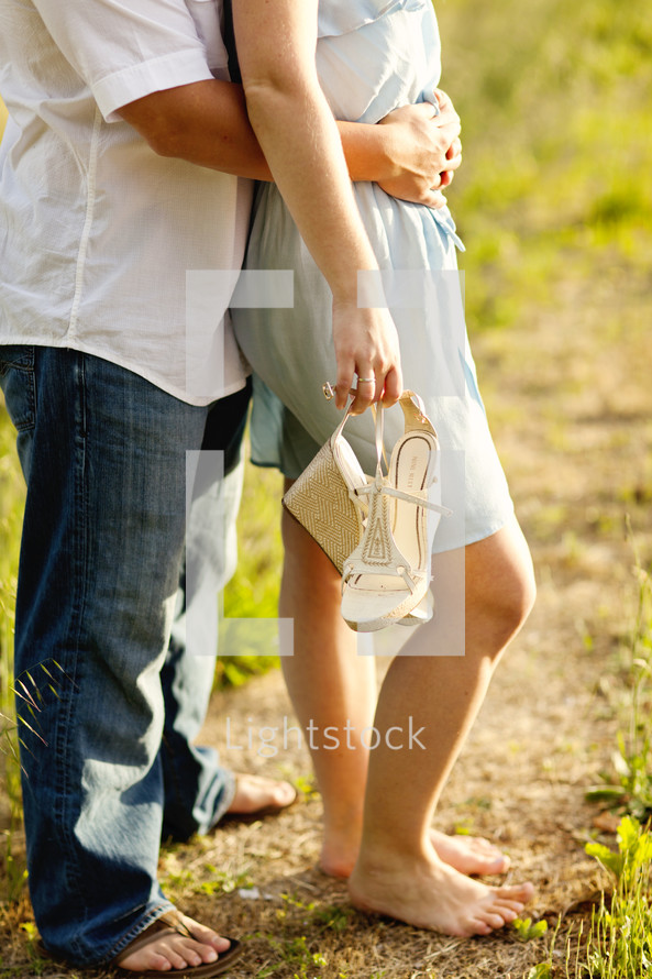 Happy couple man & woman in sandles bare feel holding shoes in hand