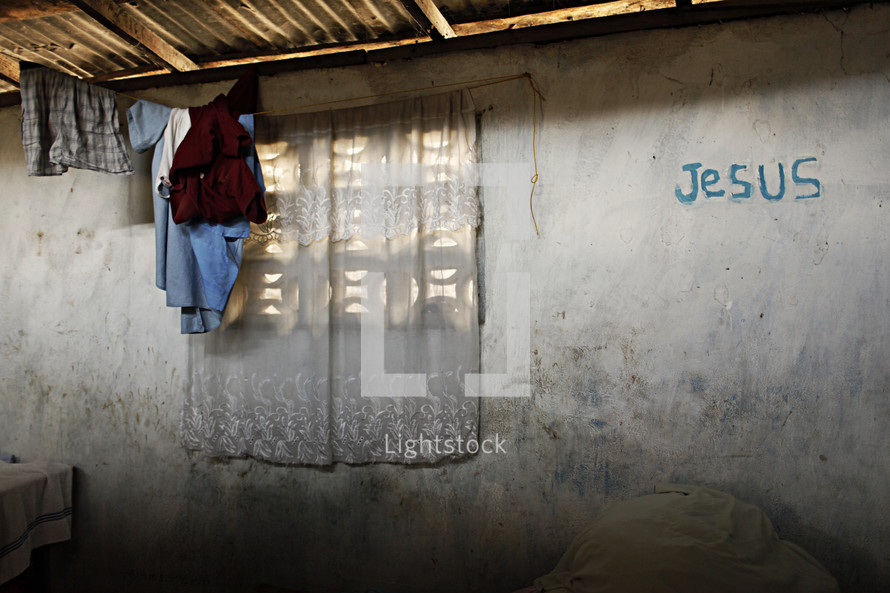 Hut with clothes hanging and Jesus written on the wall