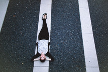 A woman lying on a white line in a parking lot.