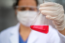 scientist holding a flask with red liquid 