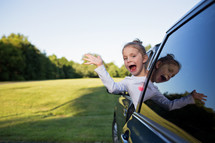 a waving child out of a car window 