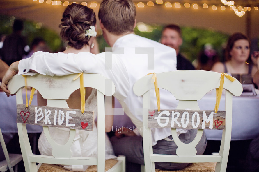 bride and groom sitting at reception - embracing