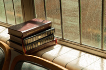 stacked books in a window sill 